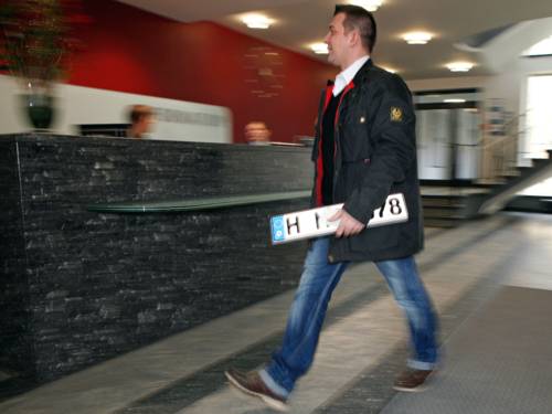 Ein Mann geht mit einem Kfz-Kennzeichen in der Hand zum Bürgerbüro der Region Hannover im Regionshaus an der Hildesheimer Straße in Hannover.