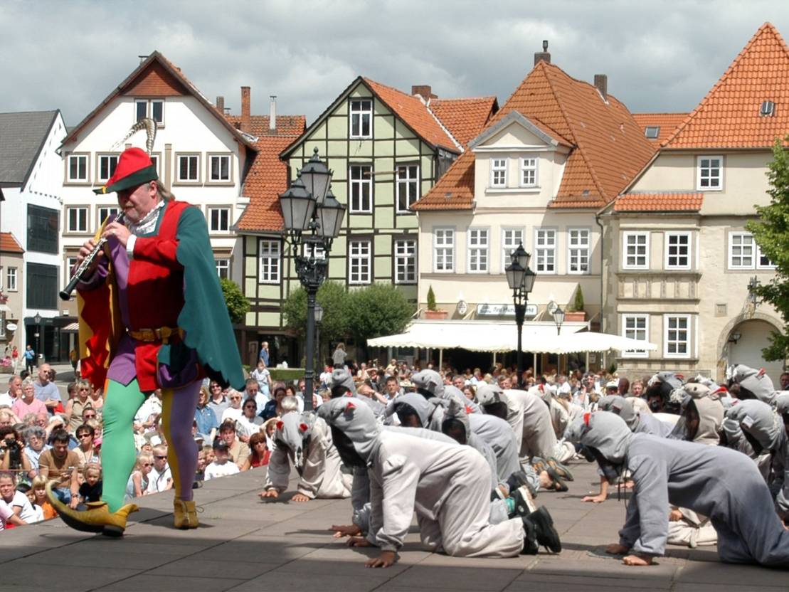 Der Rattenf&auml;nger spielt auf einer Fl&ouml;te und die kleinen Ratten folgen ihm.