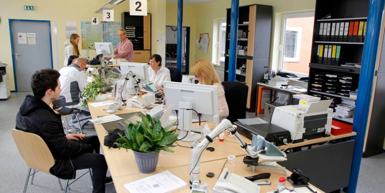 Im Bürgeramt Bemerode sitzen Einwohnerinnen und Einwohner an verschiedenen Servicestationen und werden dort von drei städtischen Beschäftigten bedient.