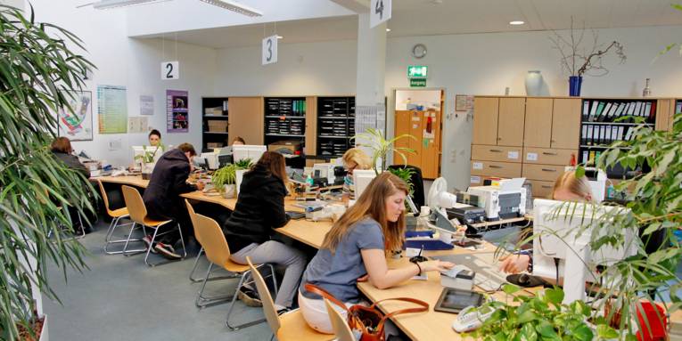 Kundinnen und Kunden sitzen gegenüber von Mitarbeiterinnen des Bürgeramtes